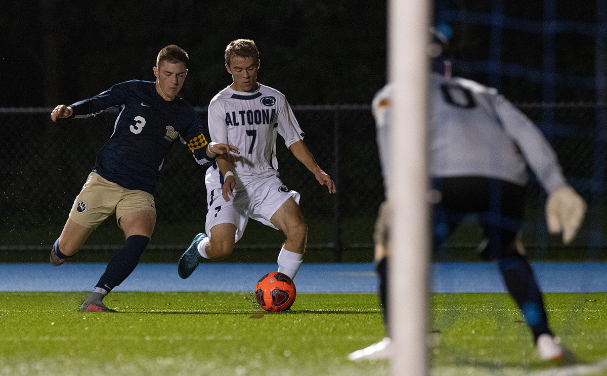 Photo (by Noah Riffe): Penn State Altoona senior Jordan Crist fends off Pitt-Greensburg's Nick Bono while approaching the goal in Tuesday night's win at Spring Run Stadium.
