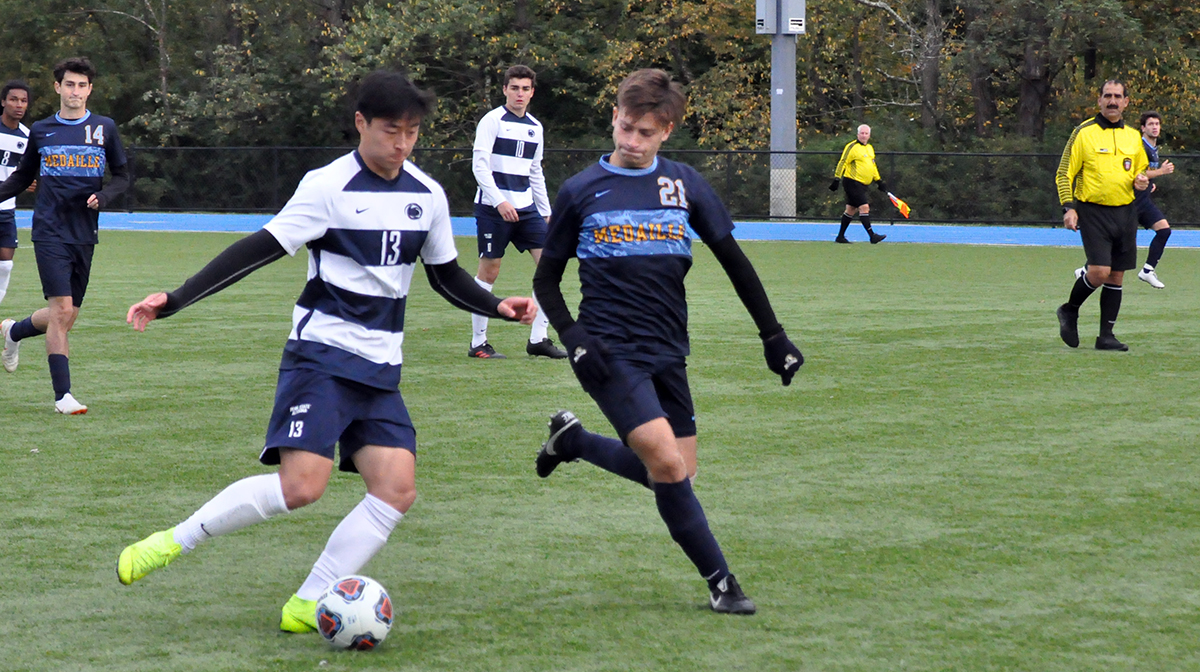 Photo (by Omer Sanchez): Freshman Jinkwon Song shields Medaille's #21 Juan Montoya from the ball during Saturday's game.