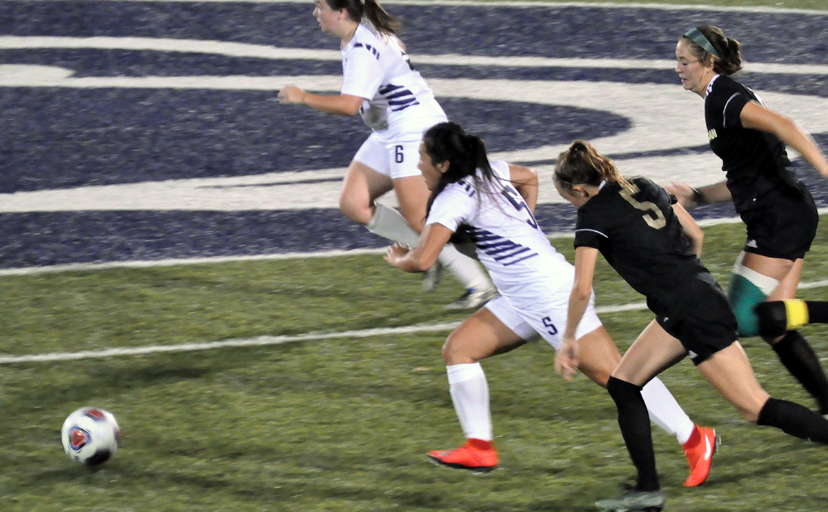 Photo: Freshman Sarah Huston races past a pair of Franciscan players near midfield during Tuesday night's game.